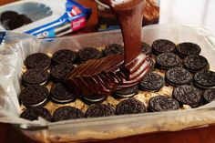 an oreo cookie being drizzled on top of chocolate frosted cookies