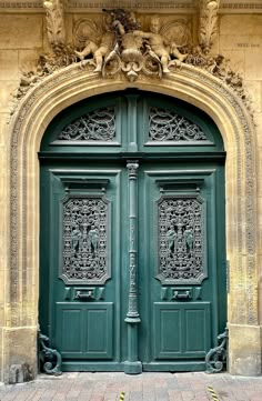 a large green door with carvings on it's sides and an arch above the doorway