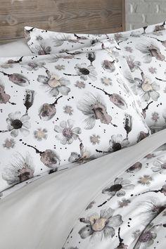 an image of a bed with white sheets and flowered comforter set on it