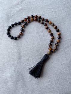 🍃every ninth bead is marked  with a 8mm green saldalwood bead (total of four) 🍃Japa mala of 45 beads  🍃Handmade tassel with the same cord that holds the beads 🍃sandalwood guru bead  🍃natural stones beads: black matte onyx  7.5 to 8mm beads light Tiger eye 8mm 🍃Microfiber bag included Brown Natural Stones Mala As A Gift, Natural Stone Rosary With Round Beads For Meditation, Rosary With Natural Stones For Meditation, Adjustable Natural Stones Rosary For Meditation, Spiritual Rosary With Round Beads For Meditation, Spiritual Rosary With 8mm Beads For Healing, Spiritual Rosary For Meditation With Round Beads, Spiritual Hand-strung Rosary For Meditation, Gemstone Beads Rosary For Meditation