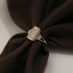 a diamond ring sitting on top of a brown cloth with a black tie around it