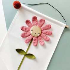 a pink flower on a white piece of cloth with a red ball attached to it