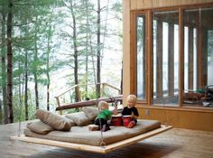 two children sitting on a swing bed in the middle of a room with wood flooring