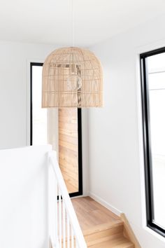 a light fixture hanging from the ceiling in a room with wood floors and white walls