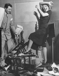 a man standing next to a woman in a room full of clutter and junk