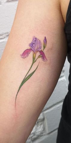 a woman's arm with a purple flower tattoo on the left side of her arm