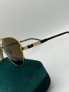 Brand new Gucci GG1163S 004 Sunglasses. Color: Gold. Shape: Aviator. Lens Width: 60mm. Lens Bridge: 13mm. Arm Length: 145mm. Lens Color: Dark Brown. Features: Adjustable nose pads, gold logos on temples. Eye Protection: 100% UVA/UVB Protection. Made in: Italy. Retail Price: $435. Arrives in Gucci jewel-toned velvet case with matching satin pouch, cleaning cloth, and authenticity card. All items are guaranteed 100% authentic and brand new. Satin Pouch, Men's Eyeglasses, Gold Logo, Eye Protection, Color Oro, Jewel Tones, Dolce & Gabbana, Mozambique, Papua New Guinea