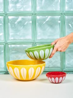 two bowls sitting next to each other on top of a white counter with green glass blocks behind them