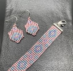 a pair of pink and blue beaded earrings, bracelet and earring on a black leather surface