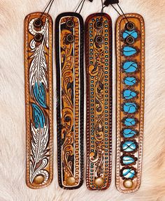 three leather bookmarks with designs on them