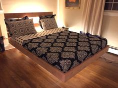 a bed with black and white bedspread sitting on top of a hard wood floor