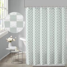 a white shower curtain in a bathroom next to a chair and table with flowers on it