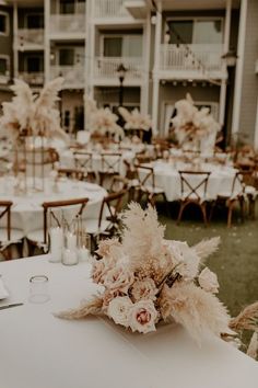 the tables are set up with white linens and tall centerpieces in front of an apartment building