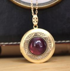 This raw brass locket has been layered with a vintage brass bezel  and set with a lovely 16mm Amethyst Gemstone cabochon.  It has been polished to a warm golden tone and sealed with a wax polish.  In time it will darken but can be polished back to golden or left to form its natural patina if desired. The locket is 30mm with 10mm bail and is hung from a matching 1x2mm brass link chain and finished with a brass lobster clasp. It will arrive in a velvet gift pouch. Antique Gold Brass Jewelry, Antique Gold Round Brass Jewelry, Antique Oval Cabochon Gemstone Necklaces, Vintage Oval Cabochon Locket Jewelry, Antique Gold Vintage Charm Jewelry, Vintage Hallmarked Oval Cabochon Necklace, Antique Gold Oval Cabochon Necklace, Brass Cabochon Jewelry For Jewelry Making, Vintage Round Gemstone Jewelry