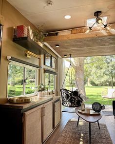 a living area with a couch, table and chairs in it next to a tree