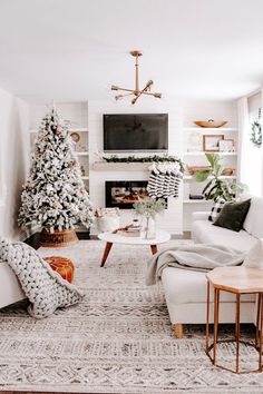 a living room filled with furniture and a christmas tree in front of a tv mounted on the wall