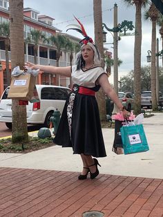 a woman dressed in costume is holding shopping bags and pointing at something on the ground