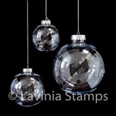 three clear glass ornaments hanging from strings on a black background with the words lavinia stamps