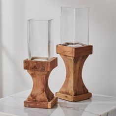 two glass vases sitting on top of a marble table