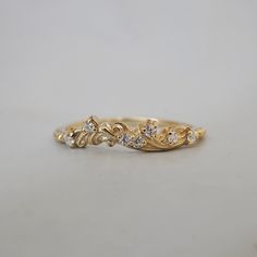 a yellow gold ring with three diamonds on the top and two leaves on the bottom