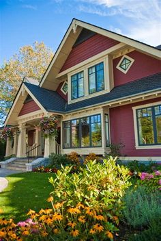 a red house with lots of windows and flowers in the front yard on a sunny day