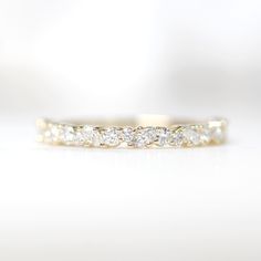 a gold wedding band with five diamonds on it's side, sitting on a white surface