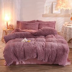 a bed covered in pink fluffy blankets and pillows