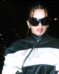 a woman wearing black and white jacket with sunglasses on her head, looking at the camera