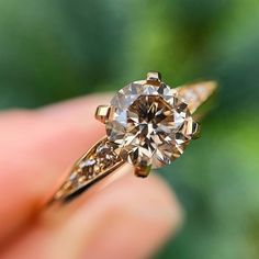 a close up of a person's hand holding a ring with a diamond in it