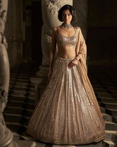 This lehenga set features all over mirror work and sequin embroidery in a linear pattern. The strappy blouse has crystal droplets at the waist. It is accompanied with a matching tissue organza dupatta.From Seema Gujral's Inara collection. DELIVERY TIMEPlease allow 8-12 weeks for your outfit to arrive. FABRIC DETAILSLehenga- Net, Blouse - Net, Dupatta - Tissue Organza Professional cleaning only. Lehenga Shoot, Tuscan Summer, Sequins Lehenga, Golden Lehenga, Sequin Lehenga, Peach Lehenga, Seema Gujral, Gold Lehenga, Mirror Work Lehenga