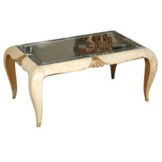 an antique coffee table with glass top and wooden legs