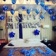 a bed with blue and white balloons on the headboard, in front of a wall that says happy birthday