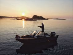 a man standing on top of a boat in the water with a fishing pole next to it