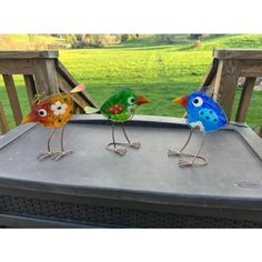 two colorful birds sitting on top of a grill