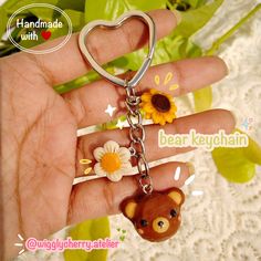 a hand holding a bear keychain with sunflowers in the shape of a heart