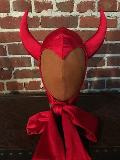 a red devil mask with horns on it's head is sitting in front of a brick wall