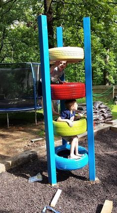 two children playing in a playground with tire tires on the ground and another child sitting on top of it