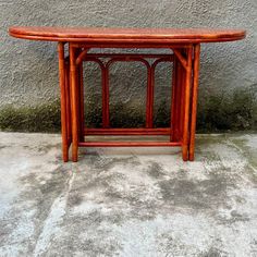 a wooden table sitting on top of a cement floor next to a gray stucco wall