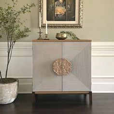 a white cabinet sitting next to a potted plant on top of a hard wood floor