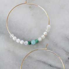 With white moonstone beads (that are said to be a feminine and sensual gemstone) and touches of malachite and amazonite, these hoops will give you all the girl power vibes you need. 45mm (about 1.75") gold-filled or sterling silver hoops with White Moonstone, Malachite and Amazonite gemstone beads packaged on a kraft earring card in a clear resealing bag gold-filled hoops are lead-free gold over brass. Gold-filled has much more gold than gold-plated and will last longer without tarnishing. Not s White Amazonite For Jewelry Making, Bohemian White Circle Jewelry, White Bohemian Circle Jewelry, White Bohemian Circular Jewelry, White Beaded Amazonite Jewelry, White Amazonite Jewelry With Natural Stones, Handmade White Amazonite Jewelry, Spiritual White Amazonite Jewelry, Gemstone Hoop Earrings