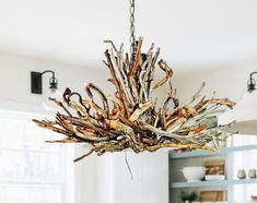 a chandelier made out of driftwood is hanging from the ceiling in a dining room