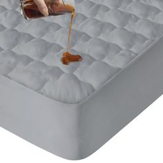 someone pouring caramel syrup on top of a mattress