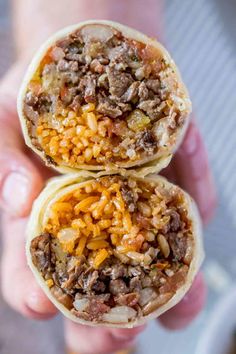 two burritos filled with meat, cheese and other toppings are held in the palm of someone's hand