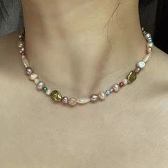 a woman wearing a necklace with multi colored pearls on it's neck and back