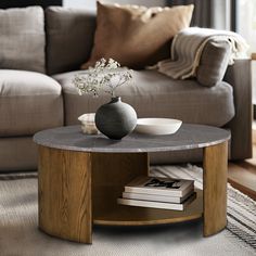 a living room with a couch, coffee table and books on the floor in front of it