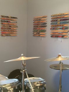 a drum set sitting in front of a wall with art on the walls behind it