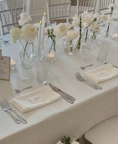 the table is set with white flowers and silverware