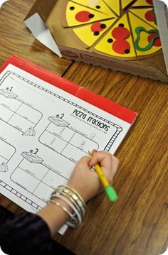 a person writing on a piece of paper next to a box with a pizza in it