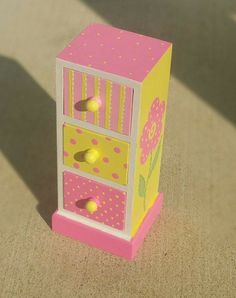 a pink and yellow toy chest sitting on top of a floor next to a wall