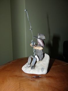 a figurine is sitting on top of a wooden table with a fishing rod